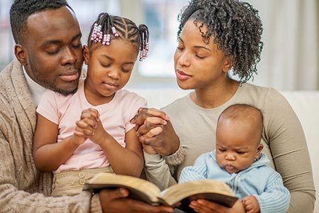 parents and child pray together about sibling