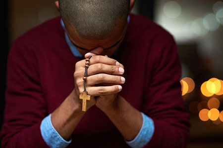 Man saying a Catholic prayer for newborn baby