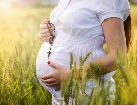 Catholic adoption story of a pregnant Catholic woman holding her rosary and keeping to her faith