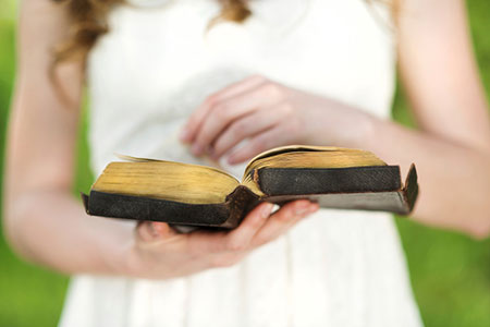 Young woman reads bible and improved her life and others in this story of Catholic adoption