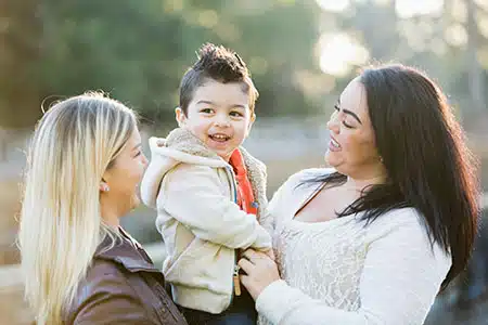 birthadoptedmomsandchild birth mother and adoptive mother share a smiling child in their contact agreement