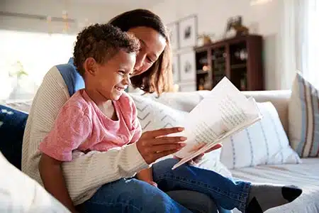 mom reads book to child talking to kids about sibling adoption