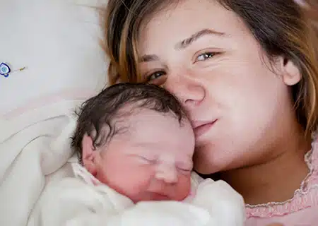 sad birth mother kisses child she is giving up for Catholic adoption