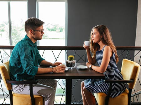 Young Catholic boyfriend and girlfriend talk together over coffee about being pregnant and what to do