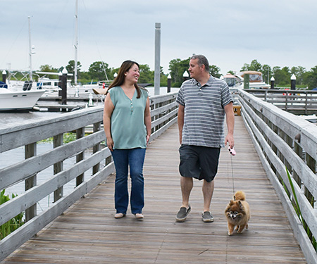 Catholic hopeful couple enjoy walking on the pier with their dog