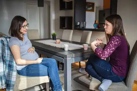 Catholic pregnant woman telling a friend she is giving baby to adoption